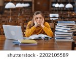 Small photo of Stressed college student tired of hard learning with books and laptop in exams tests preparation, overwhelmed high school teen girl exhausted with difficult studies or too much homework.