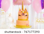 Unicorn layered cake decorated with flowers and butterfly. Pink background.