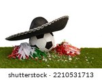 Soccer ball with a Mexican hat and green, red and white party favors on the grass of the field