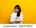 Small photo of Read a book, study with the protagonist, seek knowledge, food for thought, girl reading a book and smiling. in the photo studio yellow backdrop