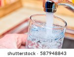 Closeup shot of a man pouring a glass of fresh water from a kitchen faucet