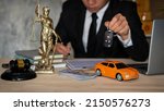 Small photo of small cars and scales Goddess of justice with hammer, money and laptop and businessman holding keys signing contract behind car title approval concept.