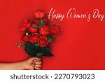 Greeting card with the inscription happy women's day. Bouquet of red Rose  flowers in a woman's hand