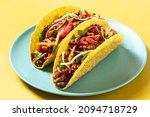 Traditional Mexican tacos with meat and vegetables on yellow background