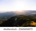 top of a mountain against the backdrop of an incredible landscape of mountains and hills at sunset. Travel destination. The lights of a sun. Incredible photo.