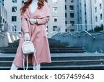 Perfect winter style. Close-up part of young woman in pink coat standing outdoors
