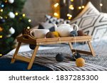Romantic Breakfast in a bed. Romantic dark bedroom decorated for New Year Celebrating. Christmas mood at home. Loft bedroom and Christmas spruces with many lights of Christmas garland 
