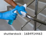 Female hand using wet wipe and alcohol sanitizer spray to clean stainless steel staircase railing.Antiseptic,disinfection ,cleanliness and heathcare, Anti Corona virus (COVID-19). Selective focus.