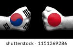 Flags of Japan and South Korea painted on two clenched fists facing each other on black background/Japan–South Korea relations concept