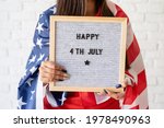 Independence day of the USA. Happy July 4th. Woman with american flag holding letter board with words Happy 4th July