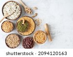 Various dried legumes in wooden bowls top view flat lay on white marble background with copy space