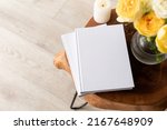 White book blank cover mockup on stylish wooden coffee table with roses bouquet, high angle view