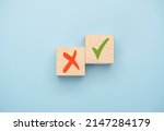 Small photo of Tick mark and cross mark x on wooden cubes. Concept of positive or negative decision making or choice of approval or rejection. chooses checkmark and x sign symbol on wooden cube block. blue