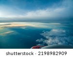 Panoramic aerial view. Beautiful sunset sky above clouds with dramatic light. Cabin view from airplane. Passenger airliner. Business trip. Commercial aircraft