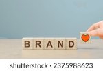 Small photo of Build brand loyalty concept. Customer loyalty or retention, marketing strategy for return customer. Increasing customer loyalty. Wooden cube blocks with BRAND text and red heart icon.