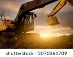 Small photo of Backhoe at construction site digging soil with bucket of backhoe. Bulldozer on sunset sky. Digger parked at construction site. Earth moving machine. Digger with bucket. Backhoe bucket loading soil.
