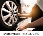 Small photo of Woman inflates the tire. Woman checking tire pressure and pumping air into the tire of car wheel. Car maintenance service for safety before travel. Tire inflating point. Filling air in the tyre of car