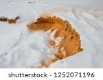 Small photo of Orange fine sand exposed on a bright white snow background. Sandstone or holystone rocks detrition in snow. Decorative winter wallpaper. Micro landslide.