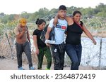Small photo of Eagle Pass, TX, USA - Sept. 20, 2023: A migrant couple seeking U.S. asylum walk down a road beside the Rio Grande River to turn themselves in to the Border Patrol.
