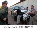 Small photo of Hidalgo, TX, USA - Sept. 18, 2023: A female Florida State trooper talks to an admitted Mexican migrant smuggler, or coyote, being taken into custody surrounded by law enforcement officers.