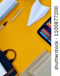 Small photo of Top view flatlay composition of lifestyle items on yellow background, planner with sharpies and paper plane on desk, copy space