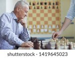 Small photo of Old man in checked shirt looking carefully at his opponents move and thinking about next retaliatory move