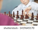 Small photo of Schoolboy in white shirt making retaliatory move in chess game with girl in purple sweater