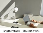 Minimal background image of unrecognizable woman using laptop on white workplace desk with focus on elegant female hands typing on keyboard in sunlight, copy space