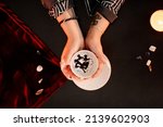 Small photo of Top down view of female fortune teller holding coffee cup in hands and reading grounds in seance