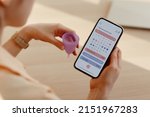 Close up of young woman calculating menstrual cycle using mobile app calendar, copy space