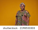 Portrait of African woman in national costume smiling at camera isolated on yellow background