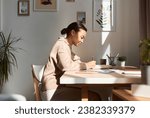 Minimal side view portrait of young African American woman writing in notebook at home with sun rays, copy space