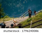 Small photo of Schynige Platte, Bernese Oberland, Switzerland - August 1 2019 : high angle view on 2 Alpenhorn players in traditional swiss outfit and tourists watching