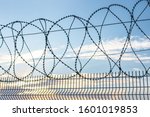 Small photo of Barbed wire against the sky. Fencing at customs. Penetration protection. Safety methods. Forbidden entry. Steel mesh as a barrier. Fence as a jailbreak warning.