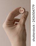 Small photo of Lotto barrel with the number 84 in a woman's hand. Female hand. Lotto keg. A two-digit number. Woman 40 years old. Symbol of the 40th anniversary. Year of birth 1984. Hold in hand. Age metaphor.