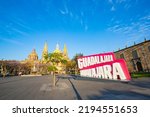 huge letters that say Guadalajara in the foreground and the Guadalajara Cathedral in the background on a calm morning