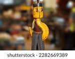 Small photo of Yellow crane hook with belt in factory industry background