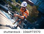 Small photo of Blurry picture of rope access industry worker wearing a white hard hat using his hand holding back up fall arrest safety device, abseiling down construction building site in Sydney city , Australia