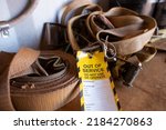 Small photo of Safe workplaces practices yellow out of service warning tag sign placing on damaged faulty unsafe to use truck tie down strap load restraint ratchet webbing