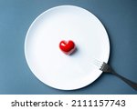 Small photo of Heartthrob or Heartbreaker concept with red heart shape on a plate and fork.