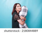 Small photo of Portrait of sleepy attractive Asian woman wearing pajamas, smiling and holding bolster