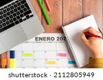 Small photo of Person writing annotations of the activities to be carried out in a notebook together with a calendar in Spanish and his laptop. Concept of time organization and obtaining objectives. High quality