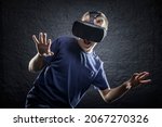 Small photo of Boy using an immersive virtual reality headset reacting and jumping to something scary he's seen