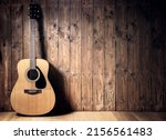 Small photo of Acoustic guitar resting against a blank wooden plank grunge background with copy space