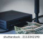 HNT cryptocurrency miner hotspot with antenna for radio connection and dollar bills as an association with the profit from mining