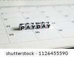 A white cube arranged in the word ’PAY DAY ' on the calendar. Payday concept.