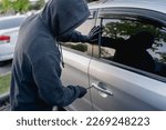 Robber breaking into a car at the parking lot.