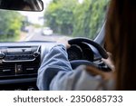 Back view of a woman driving car for summer road trip travel. Driver hand holding steering wheel for control car. Safe driving concept.