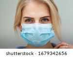 Beautiful Women In A Medical Mask. Close-up of a young woman with a surgical mask on her face against SARS-cov-2.