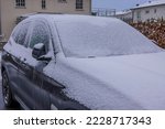 Close up of car covered in snow in private parking lot on winter day. Sweden.